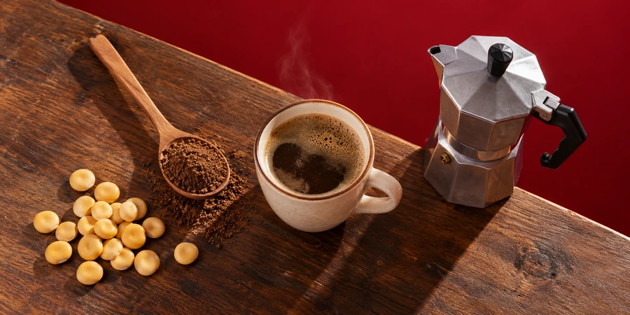 Tasse de boisson au lupin à côté d’une cafetière italienne et d’une cuillère de mouture